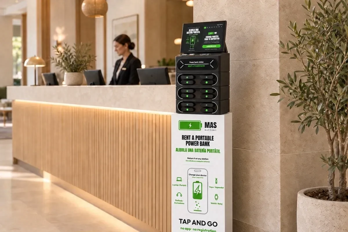 Hoste d'hotel amb maleta apropa el mòbil per llogar un power bank a una estació MasBattery de la recepció